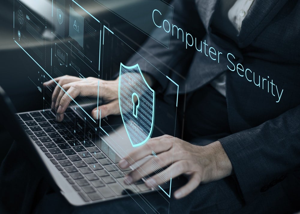 shutterstock_6331274571 a man typing near a graphic that reads computer security